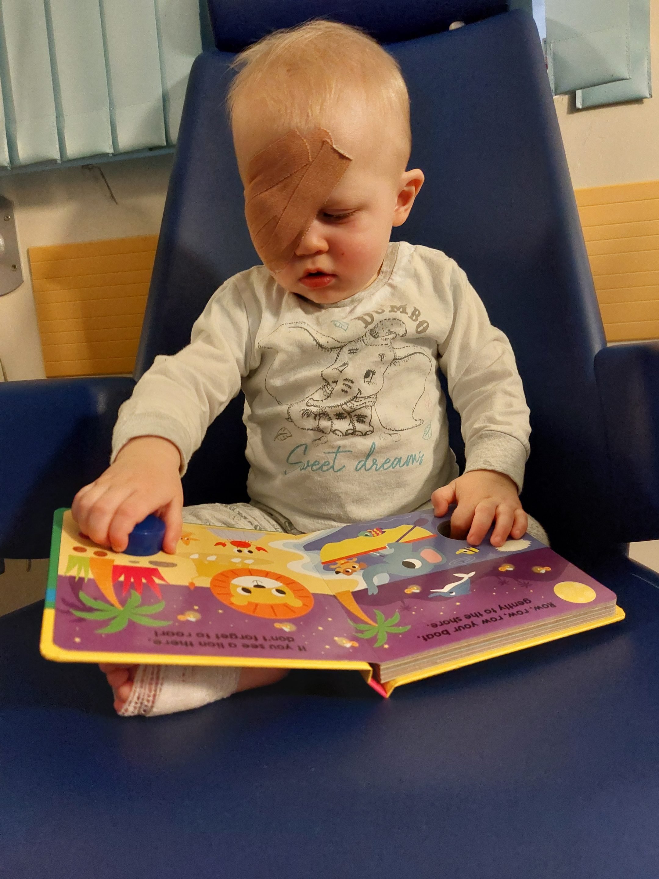 AJ reading after his operation with a board book and bandage on his eye. 