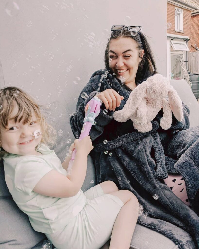 Darecy smiling with her mum playing with bubbles