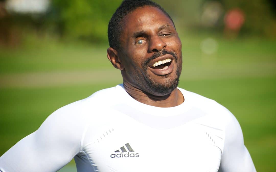 Darren is stood outside smiling outside in a white Adidas top