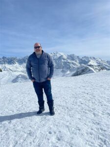 Matt is stood in the mountains on snow