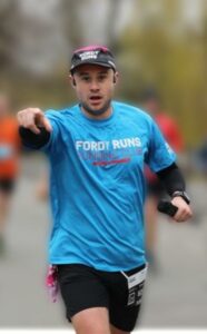 Simon is running and pointing at the camera