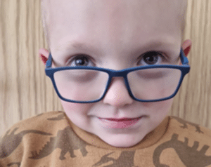 A boy wearing glasses and looking over the top of them