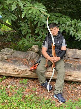 Taylor is sat outside holding a bow