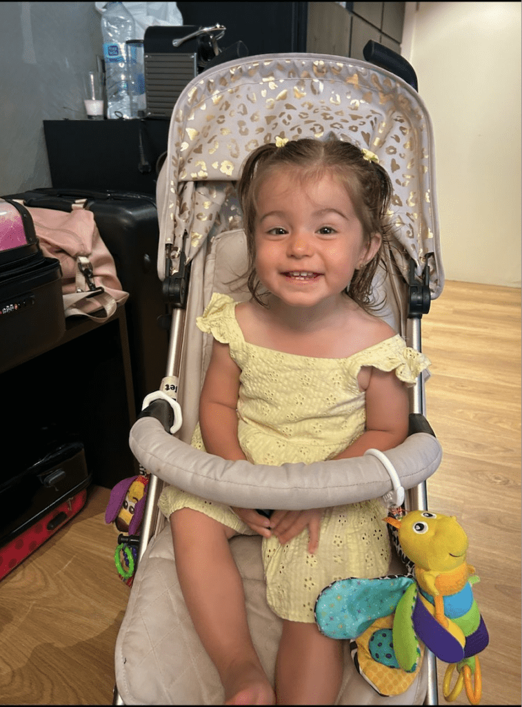 Evie is sat in a buggy smiling