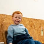 A boy sat inside smiling