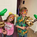 Two children are holding balloon monkeys