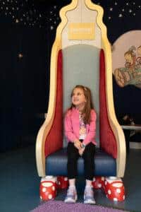 A girl is sat on a chair smiling