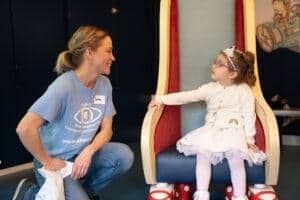 Lena is talking to a little girl sat on a chair