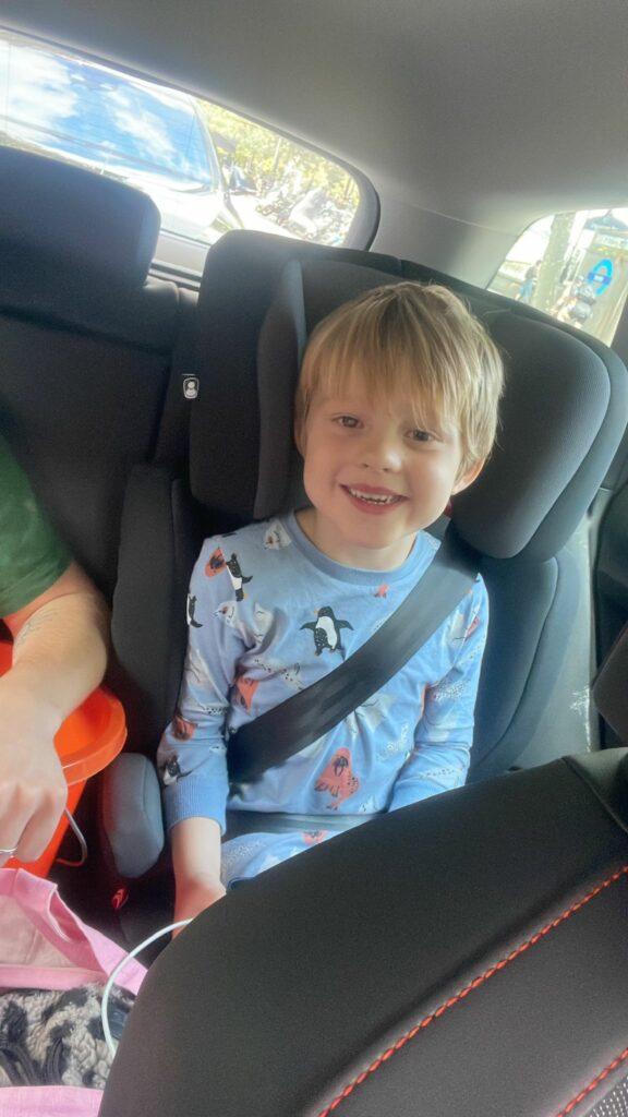 Arlo sat in the car smiling in his pyjamas