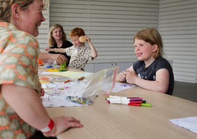 Support worker Sarah, smiling at a child across a table of arts and crafts at a childhood eye cancer trust event to help those affected by retinoblastoma