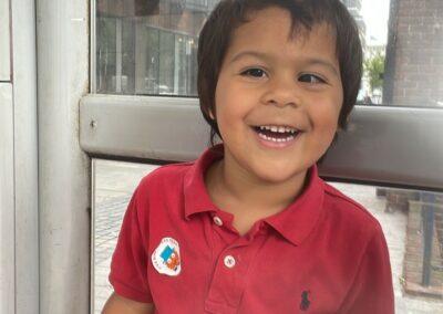 Junior is sat smiling wearing a red top