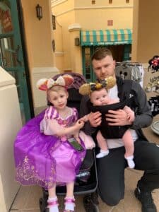 Calllum is sat with a baby and Esmae who is dressed as a princess