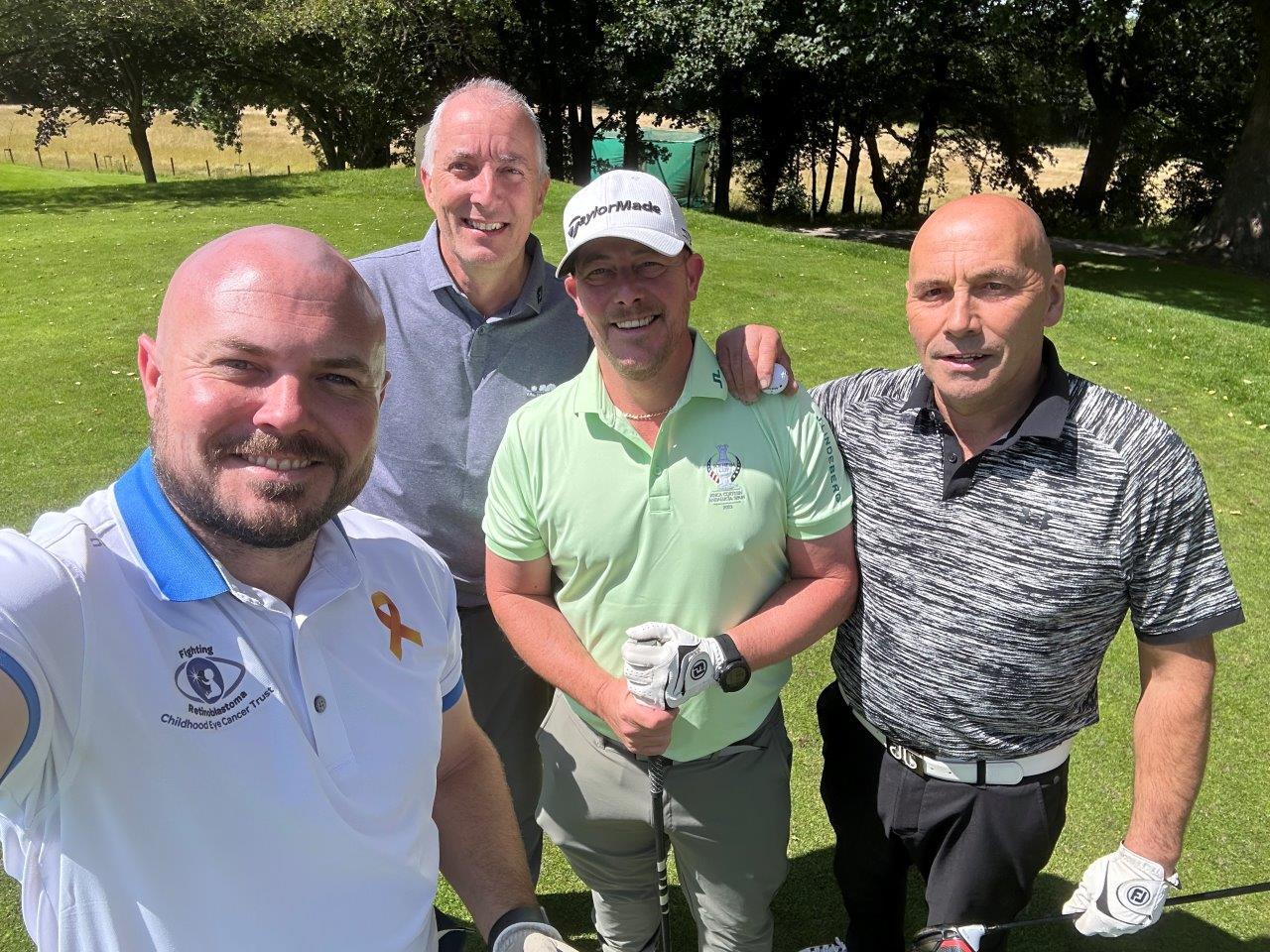 RS7718_IMG_5808 Golf day selfie from childhood eye cancer trust member with 3 friends, he's wearing a chect branded golf t-shirt.