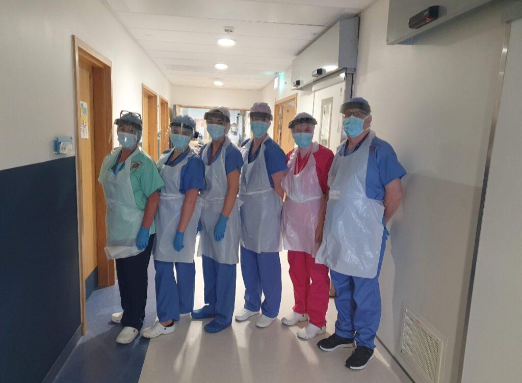 6 adult staff members are wearing scrubs and PPE in hospital
