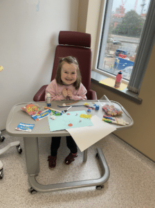 Rachel is sat at a hospital table while drawing