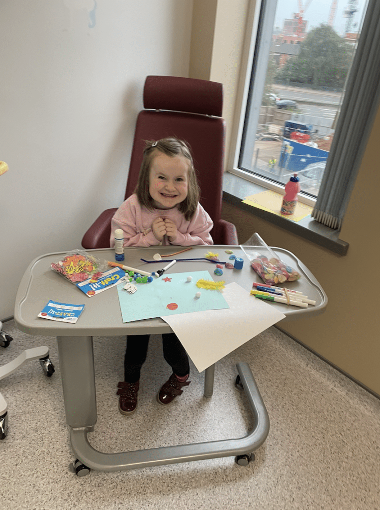 Rachel is sat at a hospital table while drawing