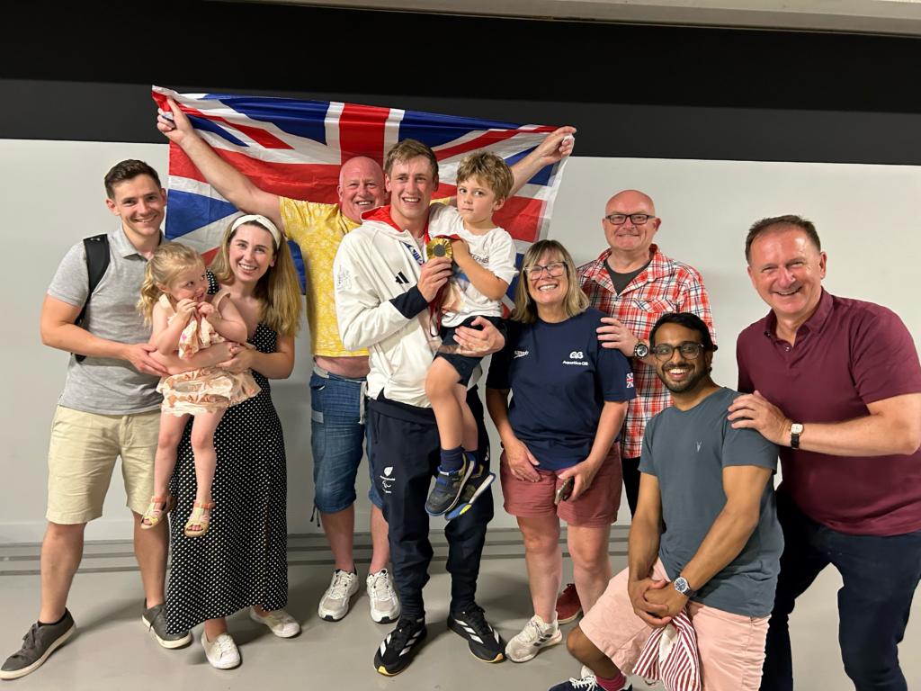 Adaline and Stephen with family and supporters holding a GB flag