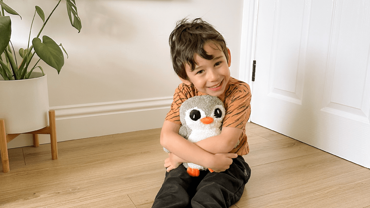 £10 Pip the penguin Little boy hugging our Pip the penguin on the floor in his house