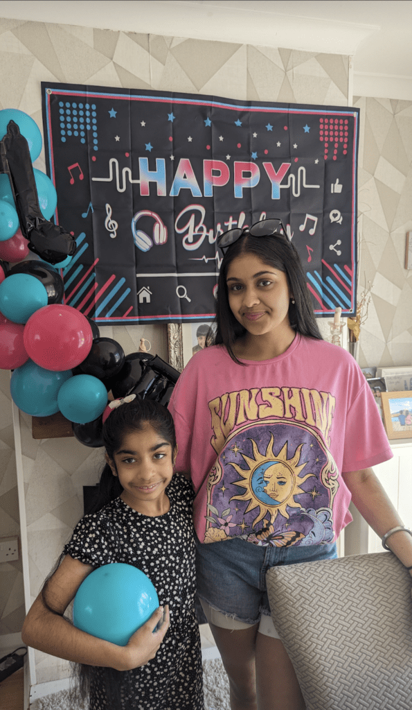 Armanie and Kriti with a happy birthday sign behind them