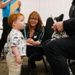 A toddler is stood with his family
