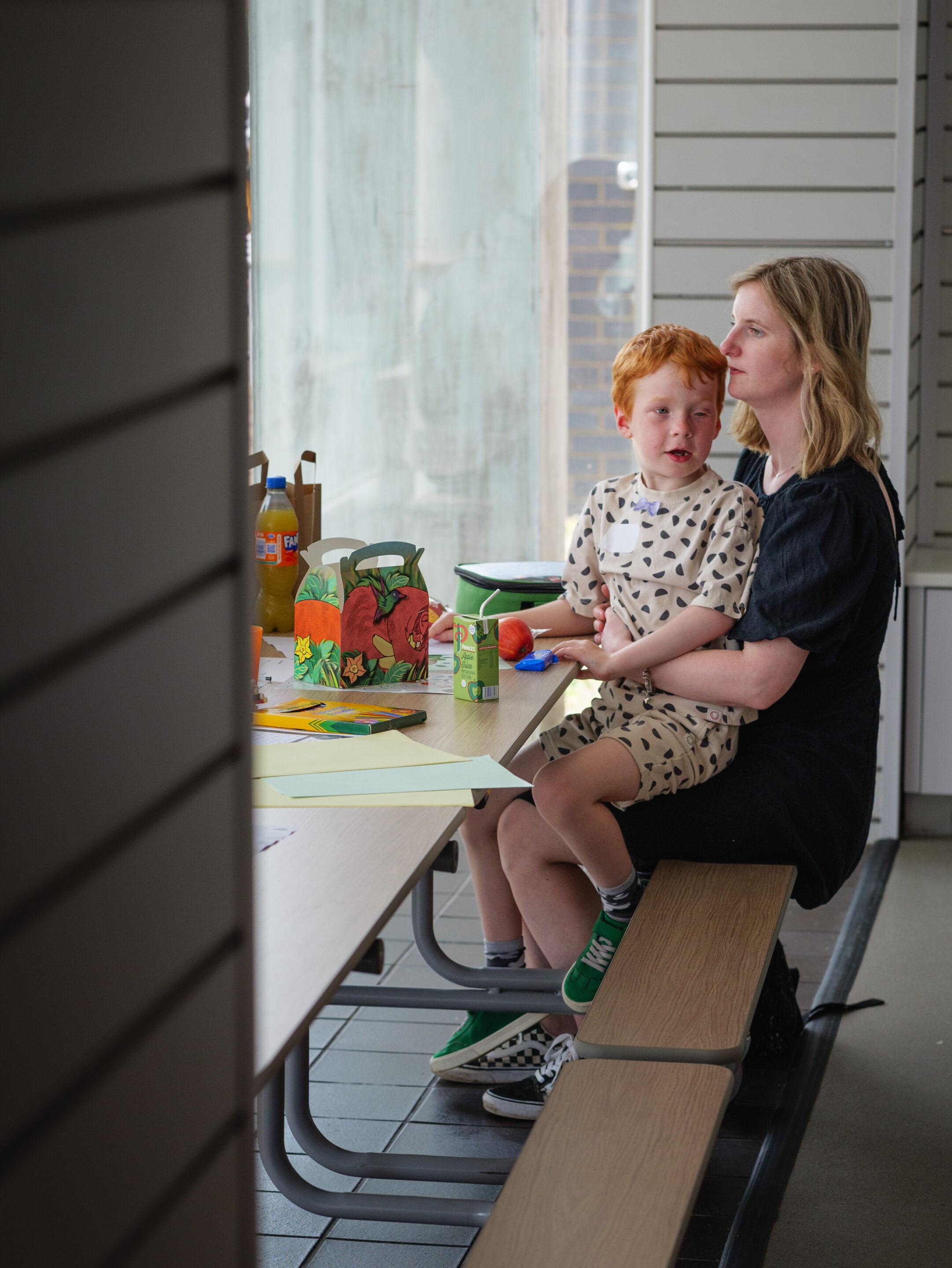 RS8193_CHECT (27 of 65) Son sitting on Mum's lap playing with crafts at a childhood eye cancer trust event