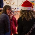 Adults are chatting, one has a santa hat on