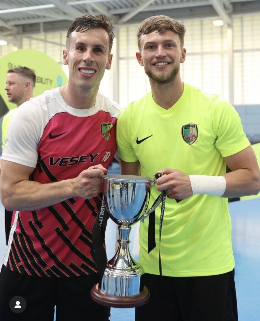 Adam holding a trophy with a teammate