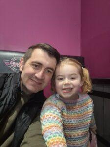 Runner Brad is smiling. Next to him, is his daughter who is also smiling