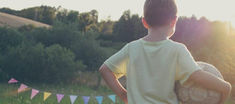 The back of a child running with a ball on a field