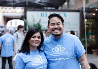 Two volunteers pose for a picture together both in chect t-shirts
