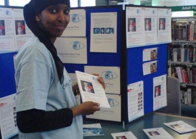 volunteer standing in front of a presentation table full of leaflets and posters about chect